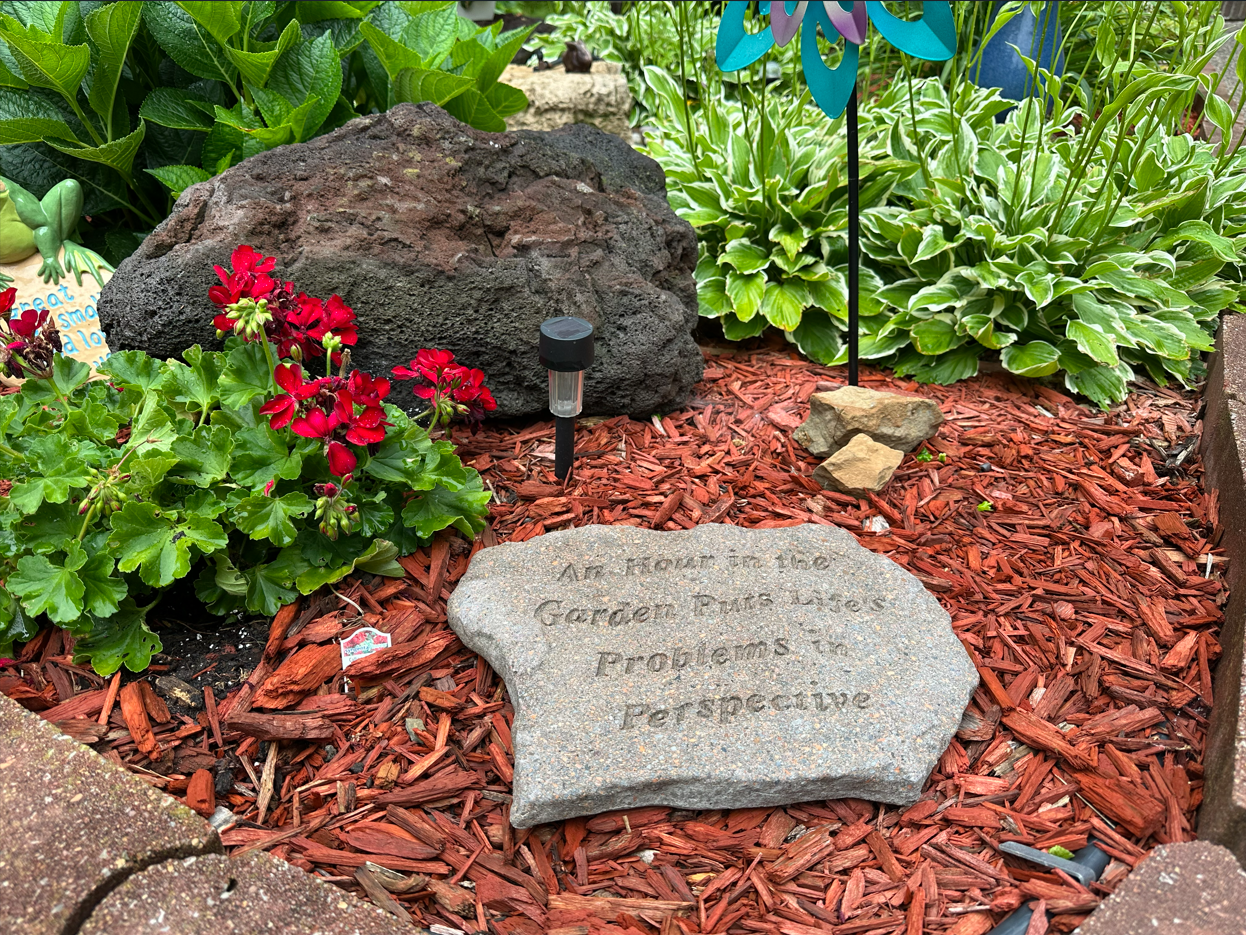 A stone in the prayer garden reading 'An hour in the garden puts life's problems in perspective'